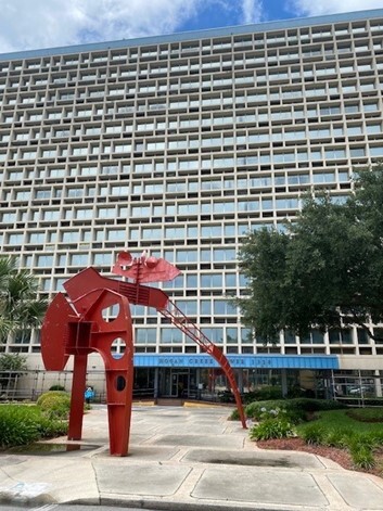 High Rise Apartment Complex with wide sidewalk and metal art in front of building