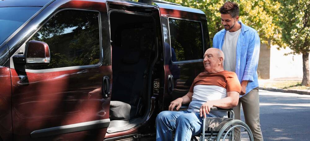 Man helping senior into van