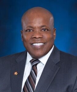 Dwayne Alexander portrait (head & shoulders) man in suit and tie smiling at camera