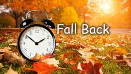 Fall Back. An alarm clock in a pile of leaves.