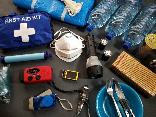 Emergency Supplies on table including first aid kit, mask, flashlight, water and more